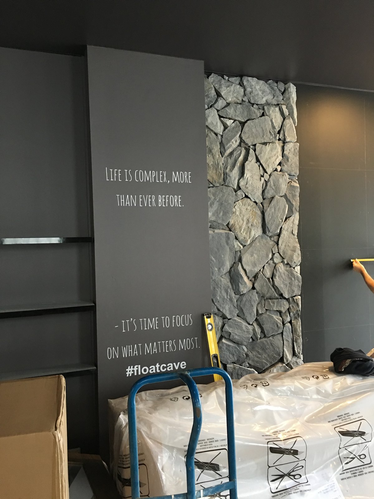 A brand message panel and stone feature wall mid-installation during the fit-out of the first City Cave centre.