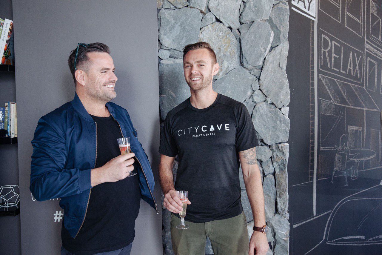 Shane Williams and City Cave co-founder Tim Butters celebrating with drinks beside the chalk mural at the first City Cave launch.