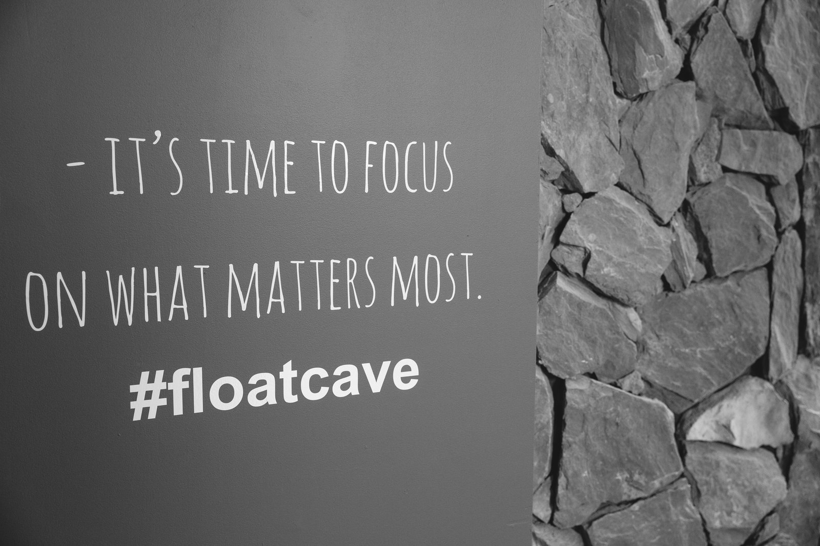 A wall at the first City Cave centre reading “It's time to focus on what matters most. #floatcave” beside a stone feature wall.